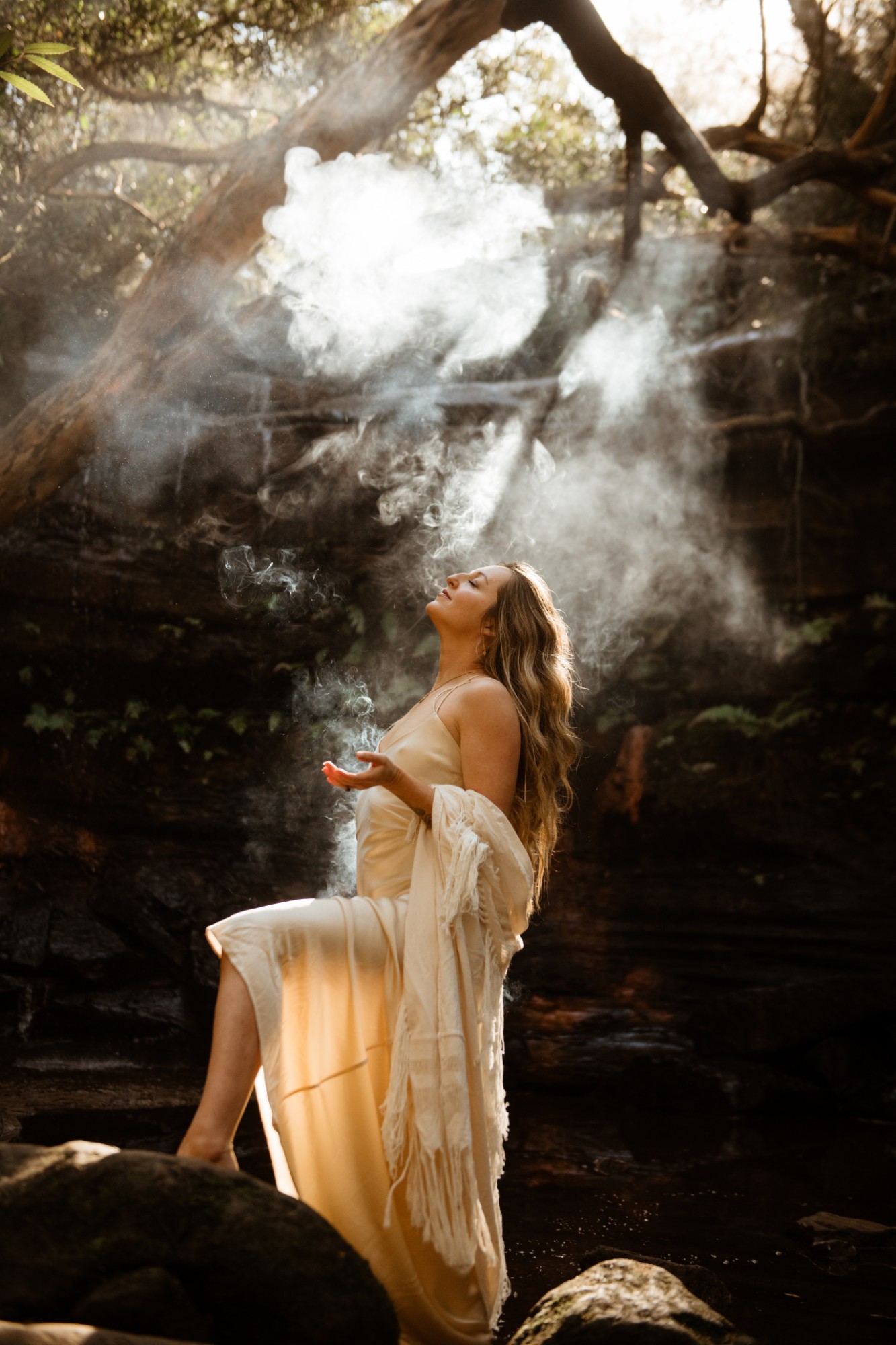 Louisa in ceremony, smoke rising through light in the trees