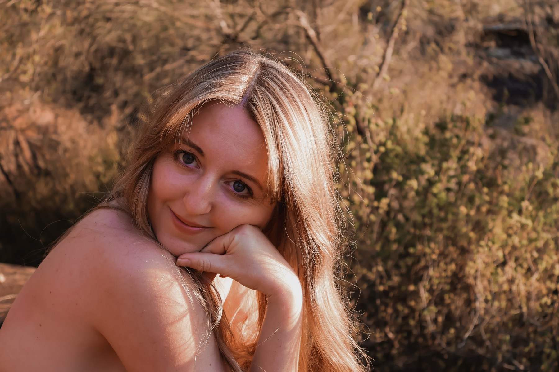 Louisa smiling, resting her chin in her hand in golden light