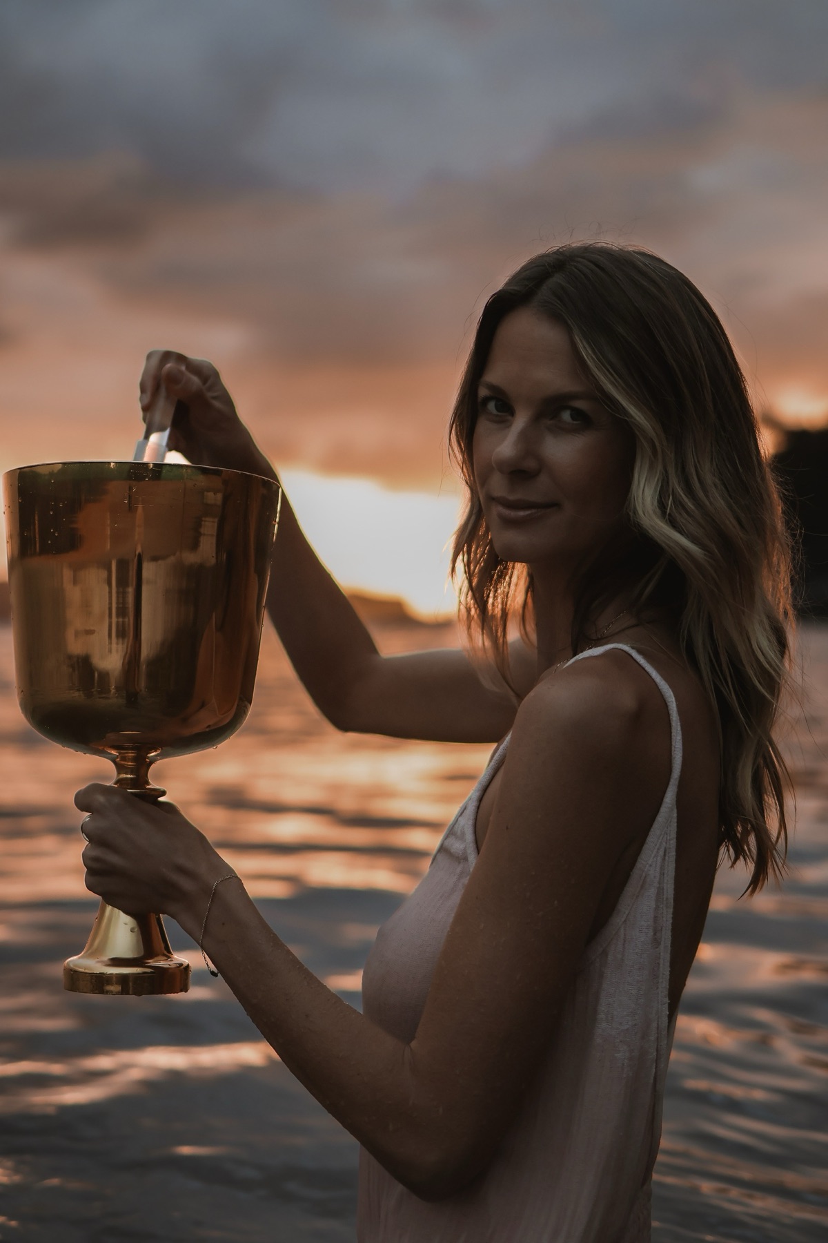 Woman holding a brass bowl in ceremony at sunset