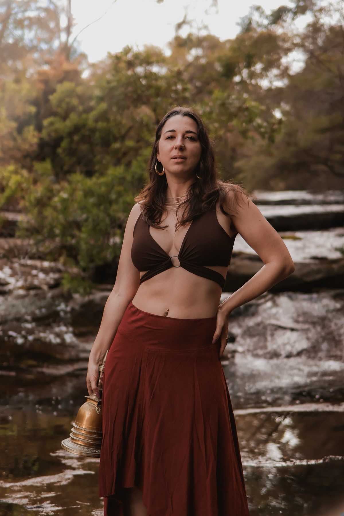 Embodiment portrait beside a waterfall, wearing a rust skirt
